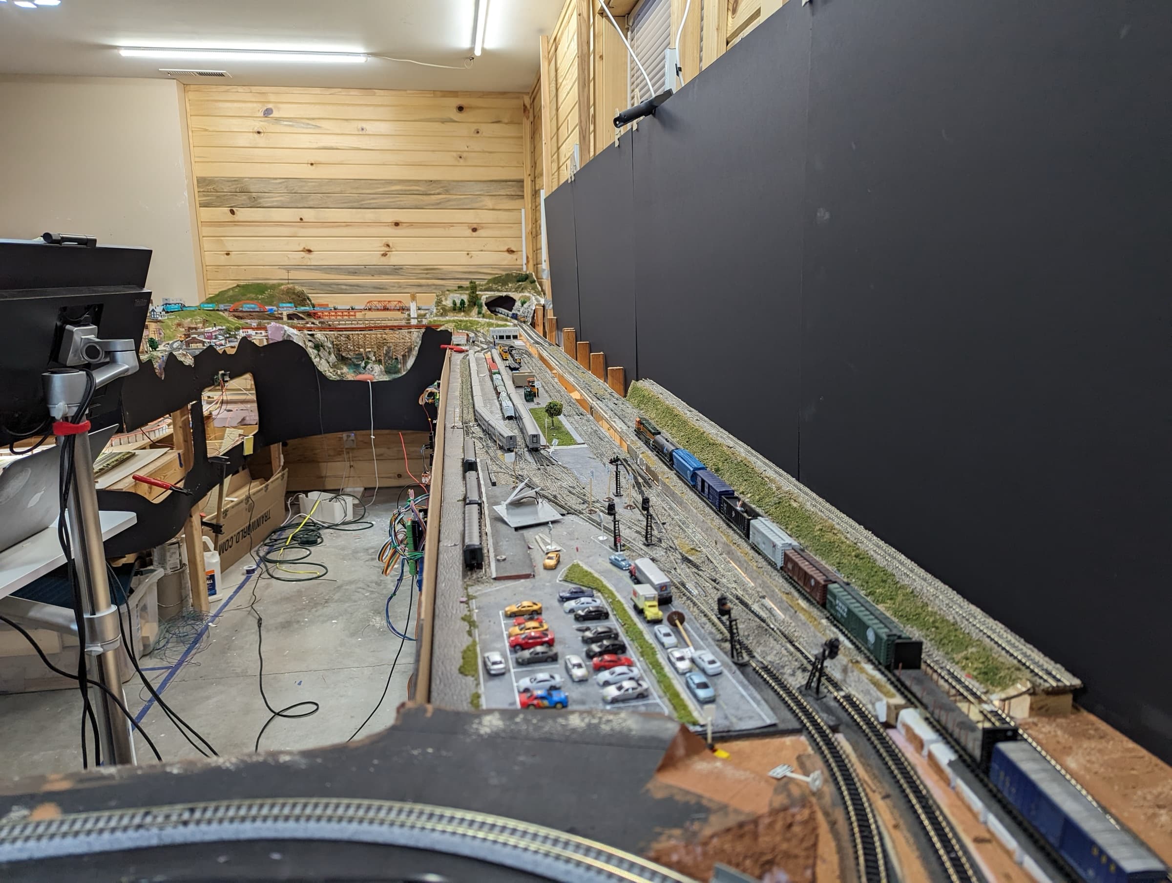 The yard running the length of the layout room, with signals, a parking lot, and freight cars along the backdrop